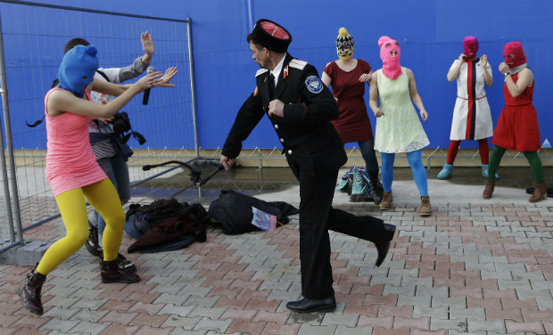 A Cossack militiaman attacks Nadezhda Tolokonnikova and a photographer as she and fellow members of the punk group Pussy Riot, including Maria Alekhina, center, in the pink balaclava, stage a protest performance in Sochi, Russia, on Wednesday - AP A Cossack militiaman attacks Nadezhda Tolokonnikova and a photographer as she and fellow members of the punk group Pussy Riot, including Maria Alekhina, center, in the pink balaclava, stage a protest performance in Sochi, Russia, on Wednesday - AP